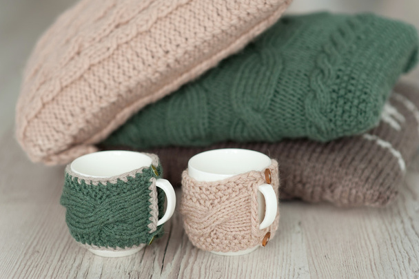 three knitted pillows and two cups  on wooden board background - Zdjęcie, obraz