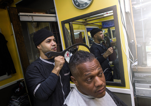 Barber montre coupe de cheveux avec miroir au client dans un salon de coiffure
. - Photo, image