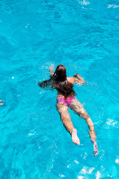 Νεαρή γυναίκα κολύμπι στο νερό των καθαρών ωκεάνιων.  - Φωτογραφία, εικόνα
