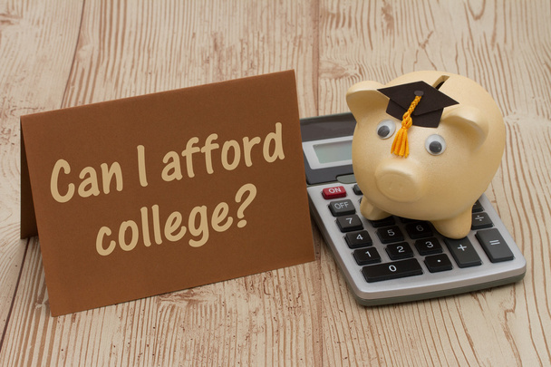 A golden piggy bank with grad cap, card and calculator on wood b - Photo, Image