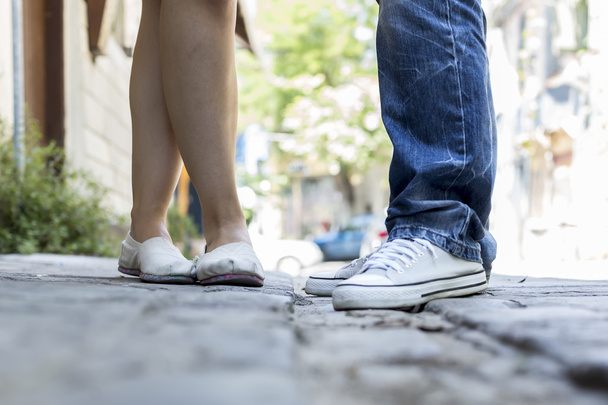 Молодая пара стоит на улице. Мужские и женские ноги
.  - Фото, изображение