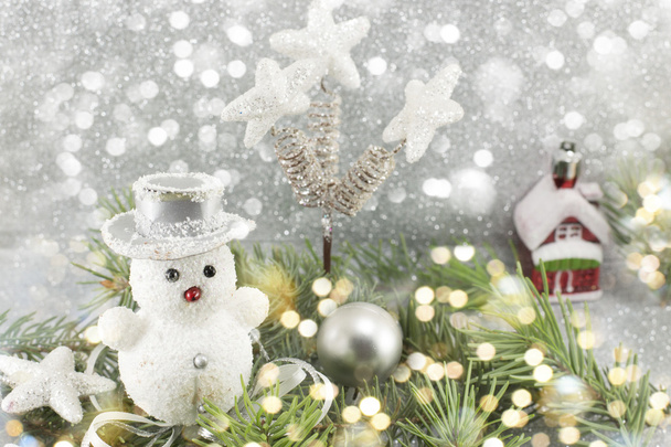 Muñeco de nieve blanco entre ramas de abeto decoradas
 - Foto, imagen