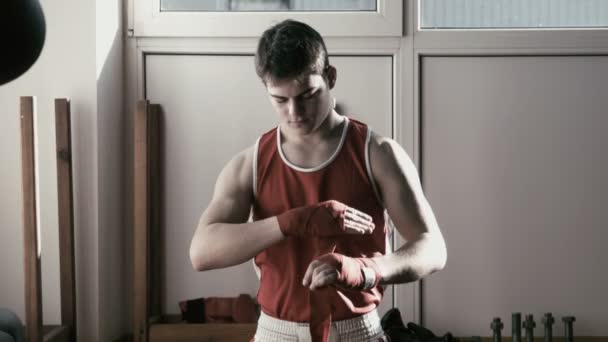O pugilista jovem puxa a atadura vermelha a mãos e luta poses
 - Filmagem, Vídeo