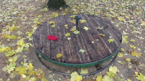 Yellow maple leaves and red glove spinning on children playground equipment - Footage, Video