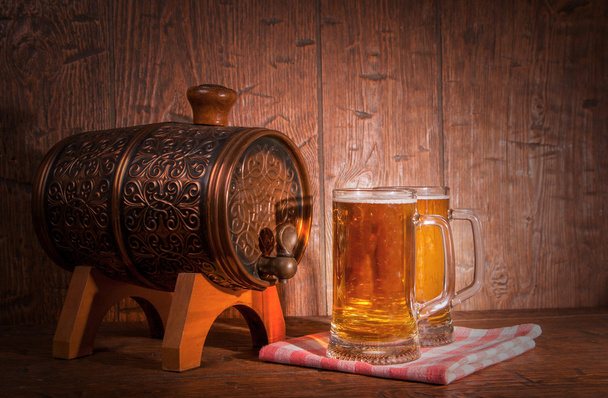 Beer mugs and barrel on a wooden background - Foto, imagen