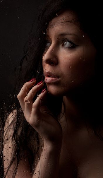 Naked girl in a wet glass on a black background - Fotó, kép