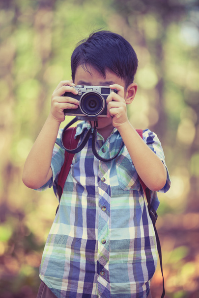 Asian boy with digital camera in beautiful outdoor. Retro style. - Foto, imagen