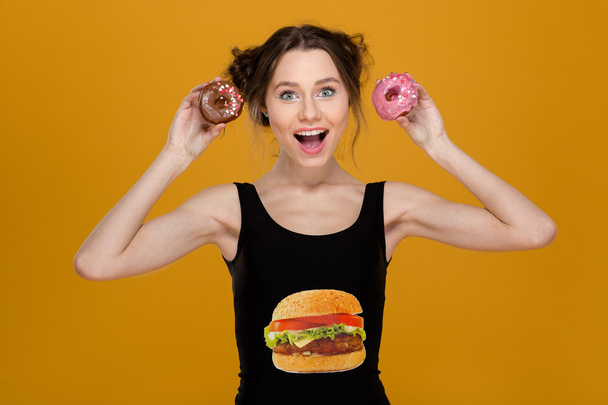 Lovely woman in black top with hamburger print holding donuts  - Фото, зображення