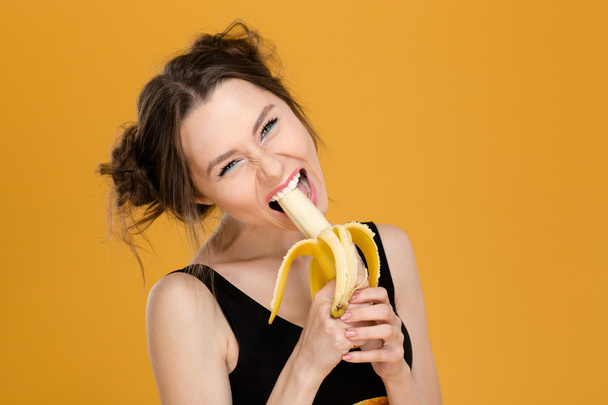 Portrait of funny beautiful young woman eating banana  - Photo, Image