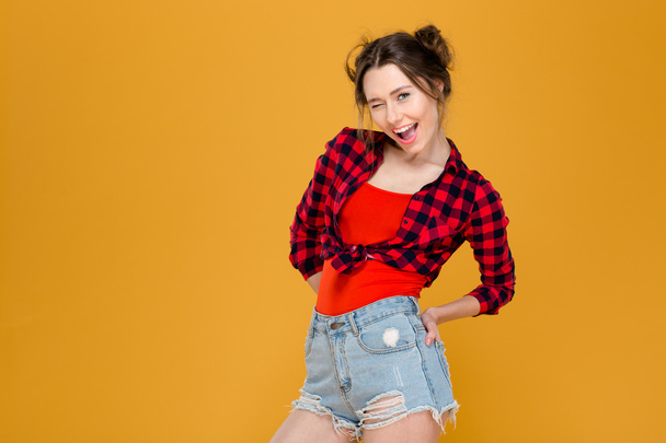 Playful happy young woman standing and winking  - Фото, изображение