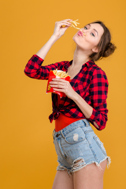 Amusing comical cute young woman having fun with french fries - Foto, imagen