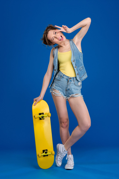 Cheerful woman standing with skateboard  - Zdjęcie, obraz