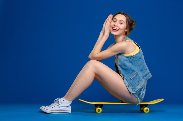 Happy woman sitting on skateboard - Valokuva, kuva