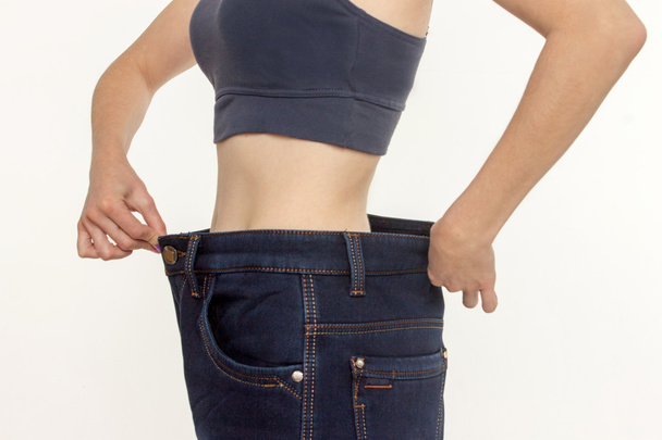  vrouw in oude jeans broek na het verliezen van gewicht.  - Foto, afbeelding