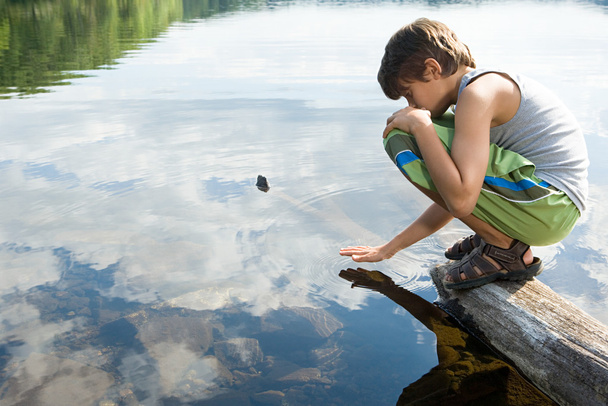 Мальчик сидит у озера
 - Фото, изображение