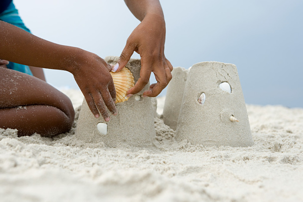 Moeder en kind een shell zetten een zandkasteel - Foto, afbeelding