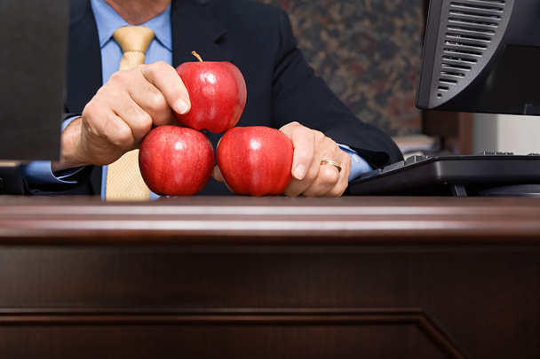 Επιχειρηματίας εξισορρόπηση μήλα πάνω στο γραφείο - Φωτογραφία, εικόνα