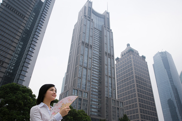 Mulher chinesa perto de arranha-céus
 - Foto, Imagem