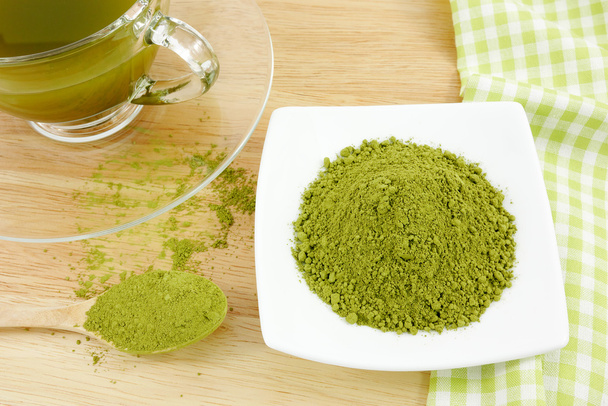 japanisches Matcha-Grüntee-Pulver auf dem Löffel und eine Tasse grünen Tee auf Holzbrett - Foto, Bild