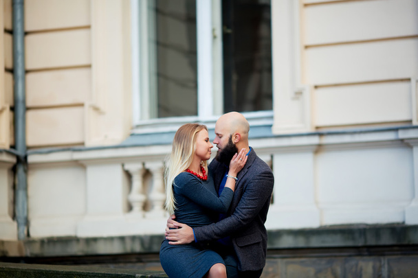 One beautiful stylish emotional couple of young woman and senior man with long black beard embracing sitting close to each other - Fotografie, Obrázek