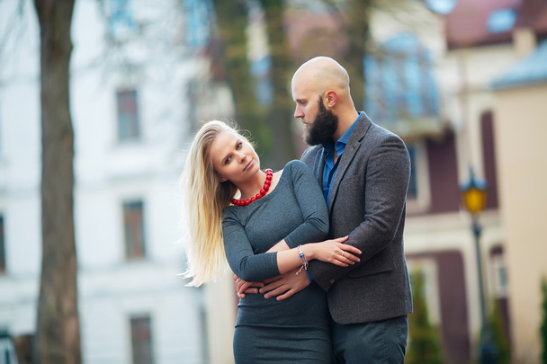 beautiful girl embraces the guy, stylishly dressed, bald man with a beard - Фото, изображение