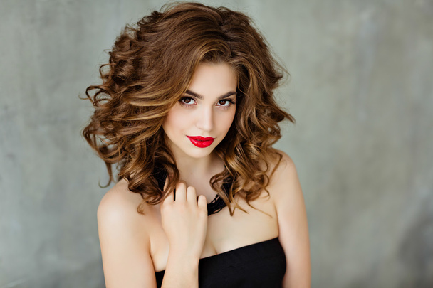 Portrait of a beautiful glamorous brunette with curly hair and bright makeup with red lipstick, close-up, beauty - Foto, Imagen