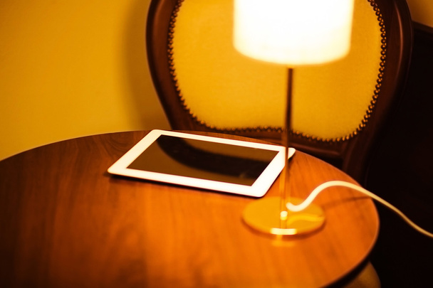 tablet on the table in the room with lamp - Photo, Image