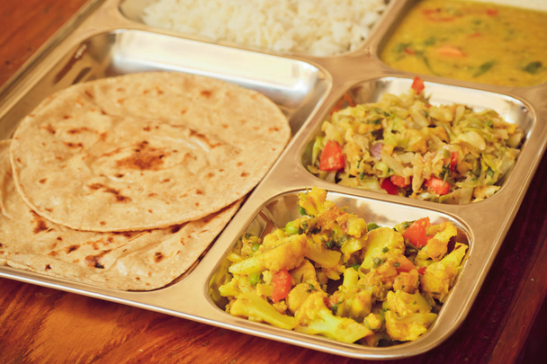 Selective focus on the metal tray with Indian dish thali, subji, rice and chapati bread - Foto, afbeelding