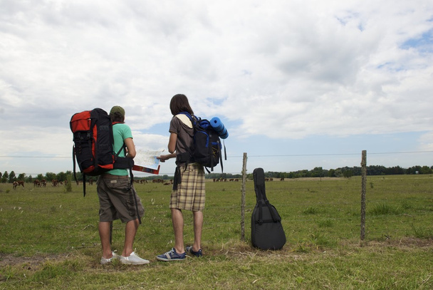 Backpackers die permanent in de buurt van hek met kaart  - Foto, afbeelding