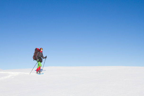 Winter hiking in the mountains on snowshoes with a backpack and tent. - 写真・画像