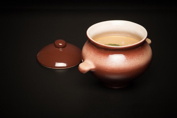 Rice soup in a clay pot on a black table or background. Toned - Фото, изображение
