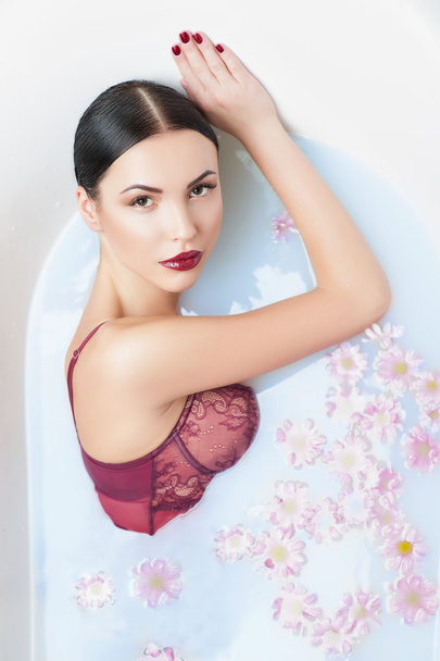 Attractive young girl is relaxing in a bathtub - Foto, Imagen