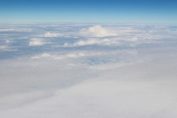 Luftaufnahme von blauem Himmel und Wolkendecke aus dem Flugzeugfenster - Foto, Bild