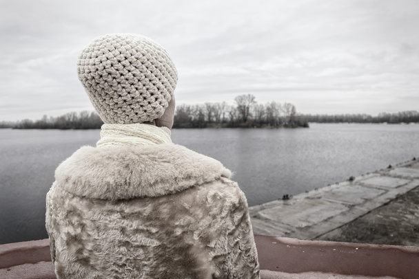 Γυναίκα ψάχνει στον ποταμό κατά τη διάρκεια μια θλιβερή ημέρα του χειμώνα - Φωτογραφία, εικόνα
