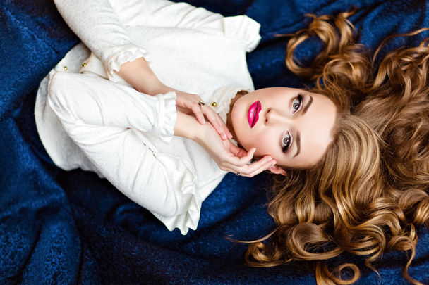 Portrait of a very beautiful sensual glamorous red-haired girl in a white blouse and a blue skirt lying on the floor in the Studio on a dark background with your eyes closed - Foto, Imagem