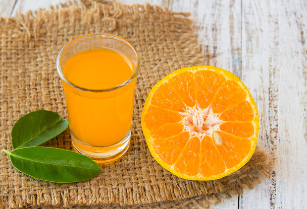 Lasi vastapuristettua appelsiinimehua viipaloidulla appelsiinilla puussa
 - Valokuva, kuva