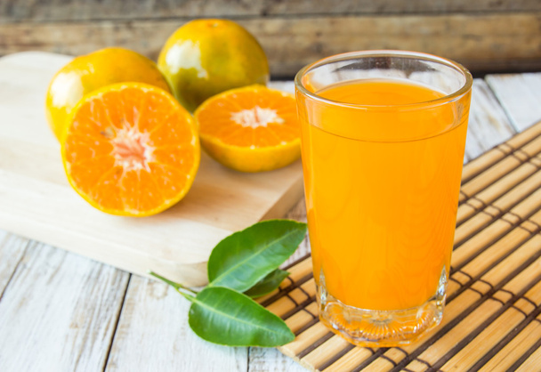 Glas vers geperst sinaasappelsap met gesneden sinaasappel op hout - Foto, afbeelding