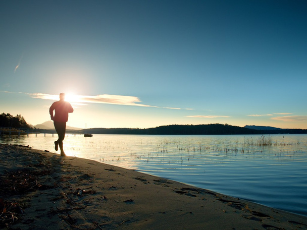 Un uomo in corsa. Maschio corridore jogging durante l'alba sulla spiaggia di sabbia
 - Foto, immagini