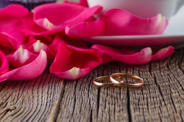 Goldene Ringe und Rosenblätter auf rustikalem Holz - Foto, Bild