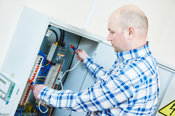 electrician works with electric meter tester in fuse box - Foto, Imagen