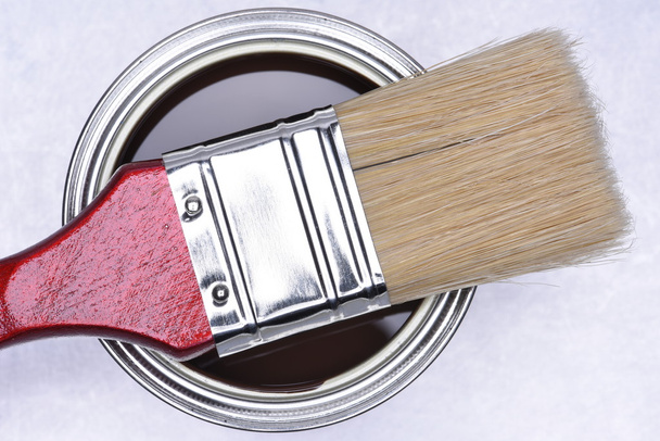 Bovenaanzicht van bruine verf kan met rood penseel - Foto, afbeelding