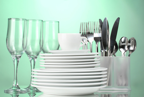 Clean plates, glasses, cup and cutlery on green background - Zdjęcie, obraz