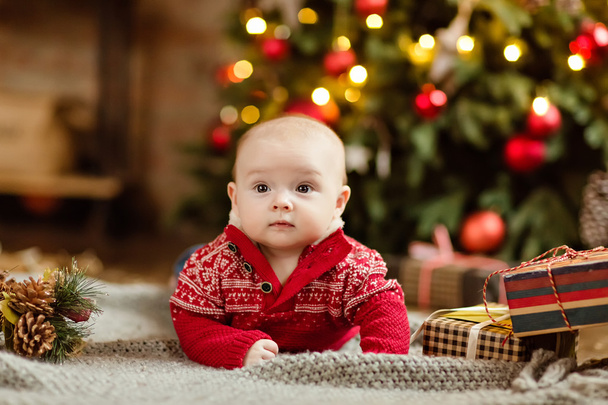 Little boy the kid in the red sweater lying on a cozy blanket on - 写真・画像