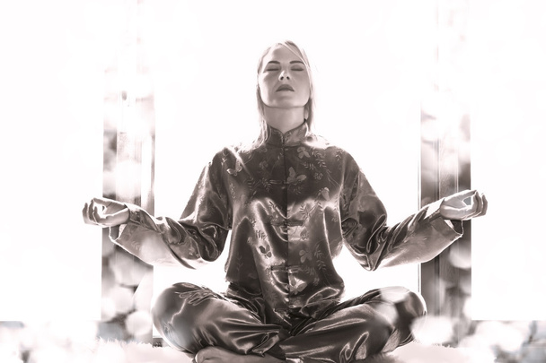 Young woman in pajamas sitting in the lotus position and meditat - Foto, Imagem
