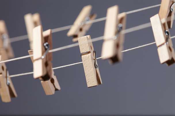 wooden clothespins on rope over grey background, close-up  - Photo, Image