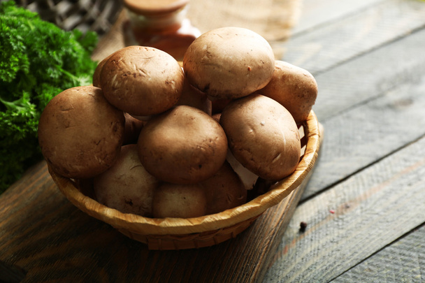 Mushrooms in basket on wooden surface - Fotó, kép