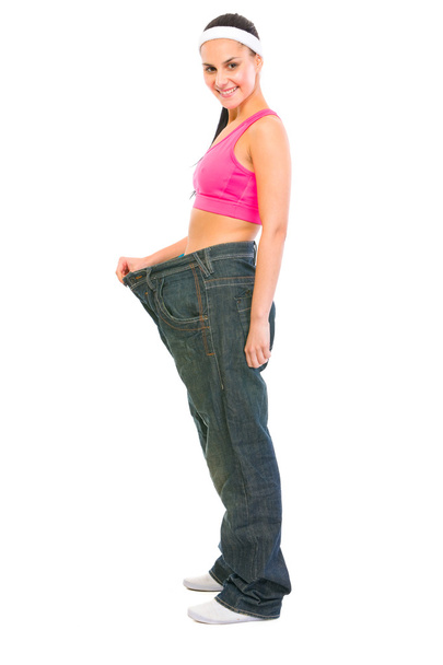 Slim girl pulling oversize jeans. Weight loss concept - 写真・画像