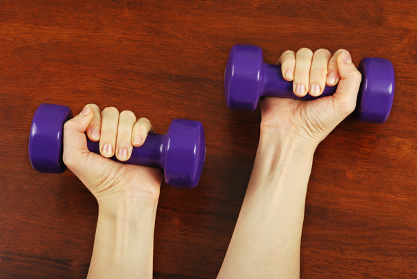 Beautiful hand of a young girl with dumbbells - Photo, image
