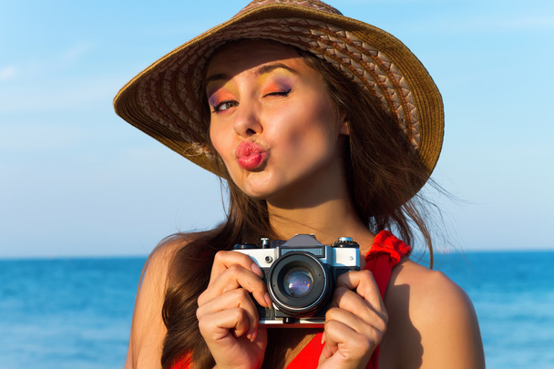 Outdoor summer portrait of young pretty woman looking to the ocean at tropical beach, enjoy her freedom and fresh air, wearing stylish wide hat and clothes.Enjoying sunset - Photo, image