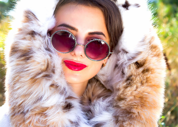 Fashion close up Portrait of attractive stylish woman with red lips wearing fur coat and trendy retro sunglasses - Фото, зображення
